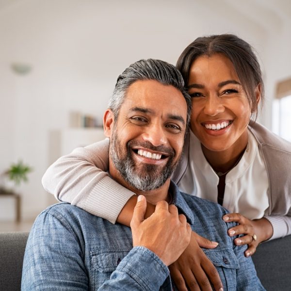 Portrait,Of,Multiethnic,Couple,Embracing,And,Looking,At,Camera,Sitting