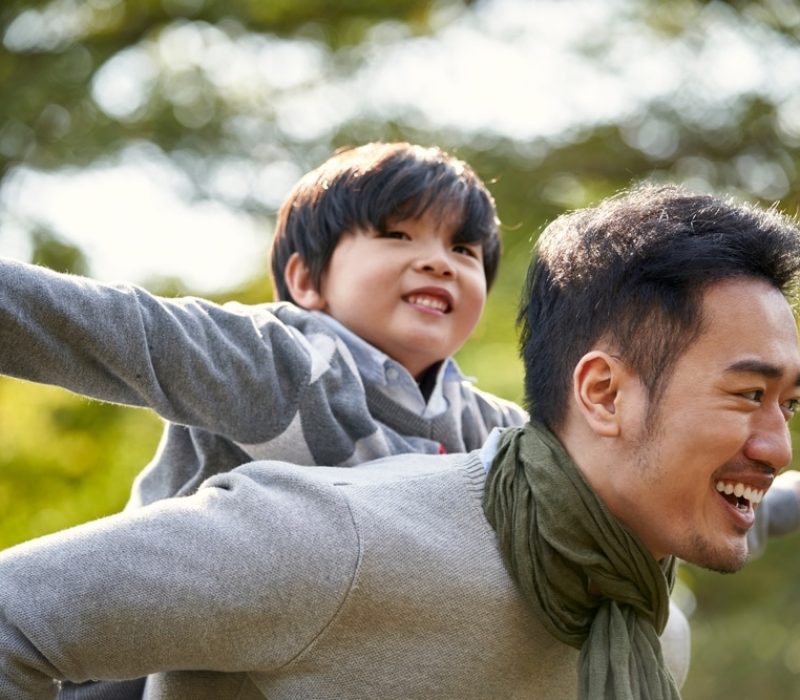 Young,Asian,Father,Carrying,Son,On,Back,Having,Fun,Enjoying